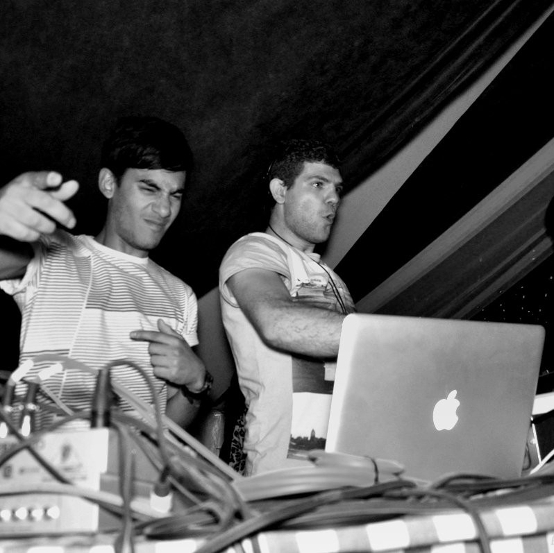 two men stood behind dj desk