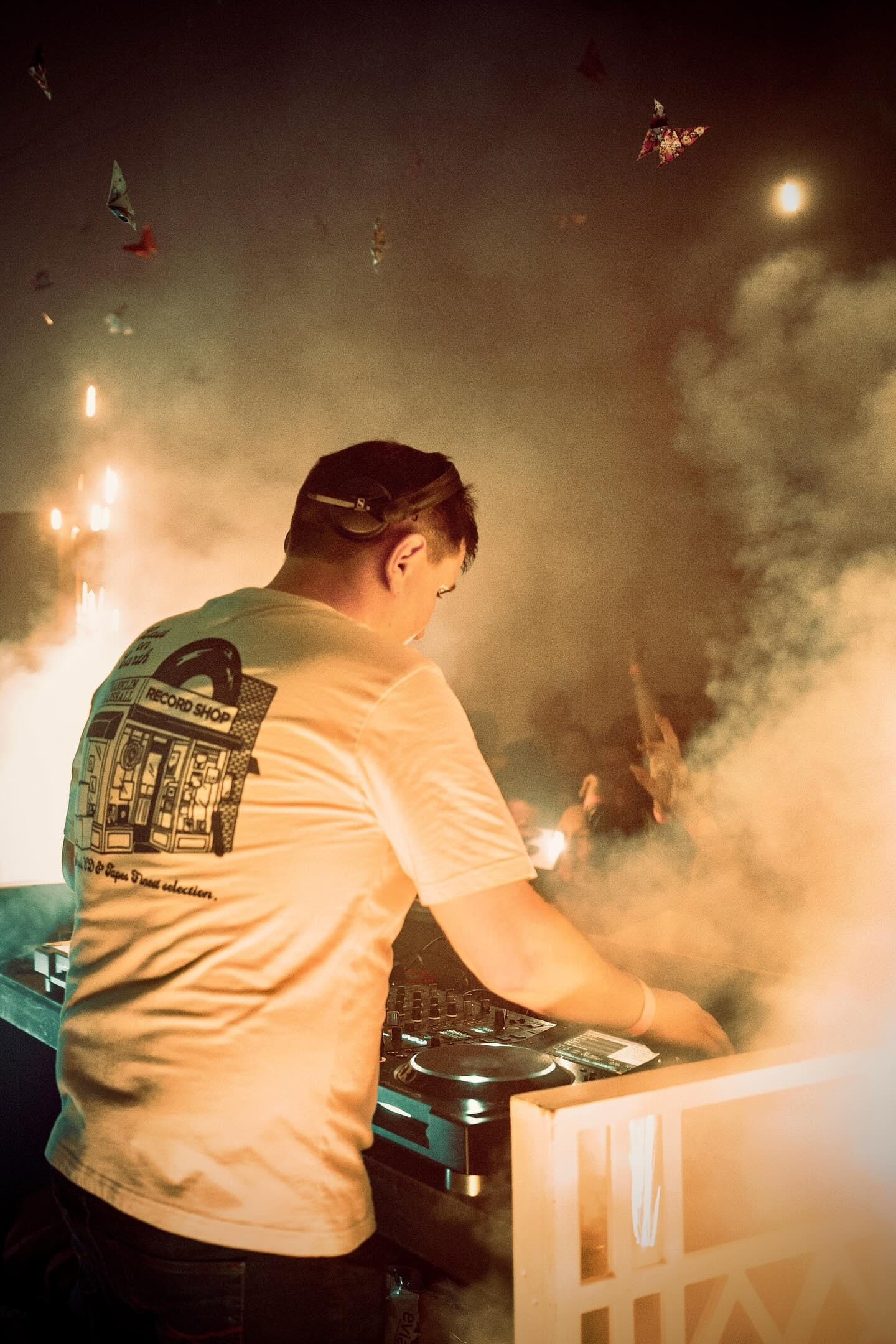 Mark facing the crowd, behind a dj deck